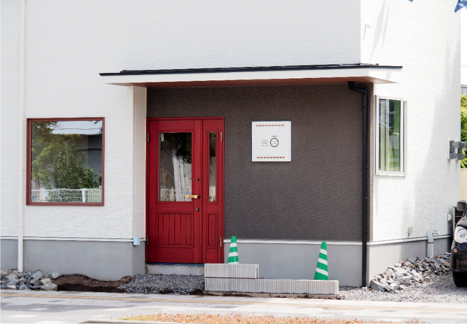 赤い木製の扉と看板が目立つ位置に。